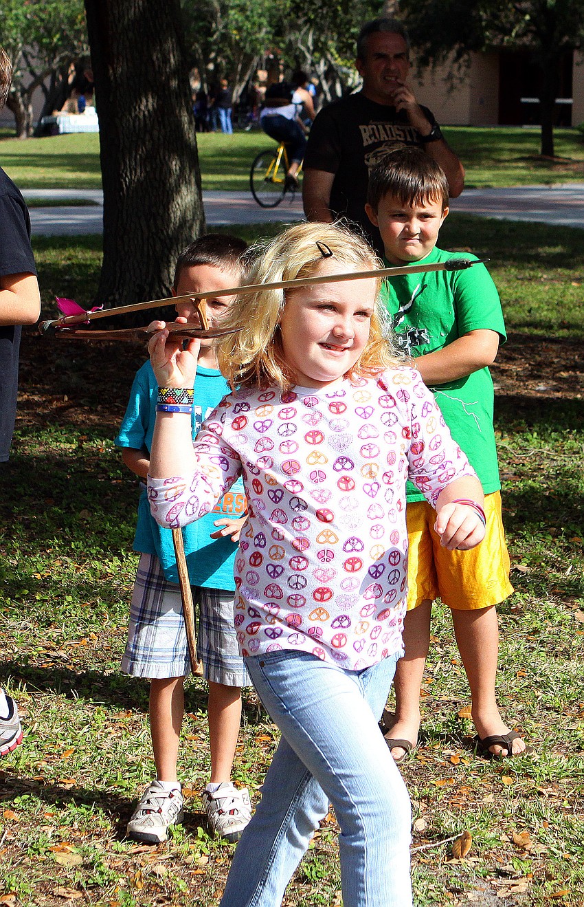 Teagan Wyvell, 8, throws an atlatl with an arrow.