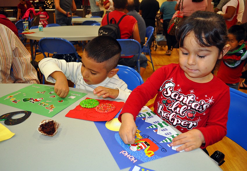 Jeffery, 4, and Shanell, 3, Zamirrpa work on decorating pieces of paper with holiday stickers.