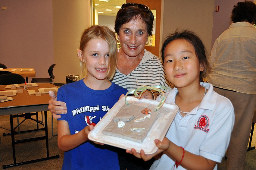 Tara Track, 8, Judy Pirkey and Bari Namgoong, 9, show off a Florida fossil plaque they all worked on together.