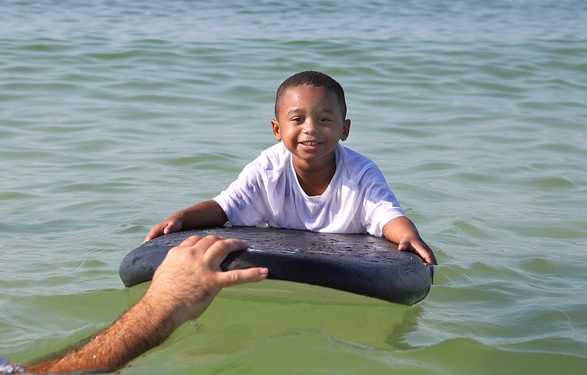 Caiden Woodward, 4, smiles big prior to having his surf guide, Mark Weeks, send him off to ride a wave during the Hang Ten for Autism surf event Saturday, Sept. 17, at the Siesta Key Public Beach.