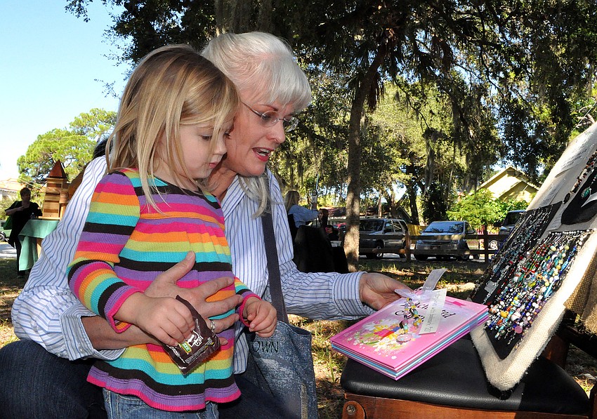 Rylie Richter, 3, and her grandmother, Cynthia, look at things at For the Love of Beads' table, Saturday, Nov. 12, during Pioneer Day.
