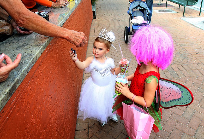 Raven Whitefield, 3, reaches for another piece of candy, while her sister, Piper, waits for her to head to the next destination, Monday, Oct. 31, during the Safe Kids trick-or-treating event in Siesta Key Village.