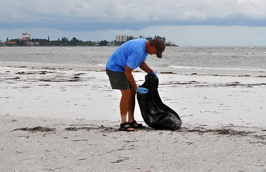 Brian Patti, from AZ, picks up trash on the beach during the Barefoot Wine Beach Cleanup Thursday, Sept. 8, at Ted Sperling Park.