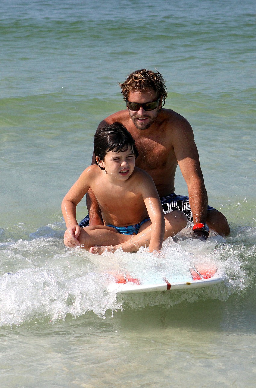 Dean Dougherty rides a wave in with Max Whittemore, 8, Saturday, Sept. 17, at the Siesta Key Public Beach.