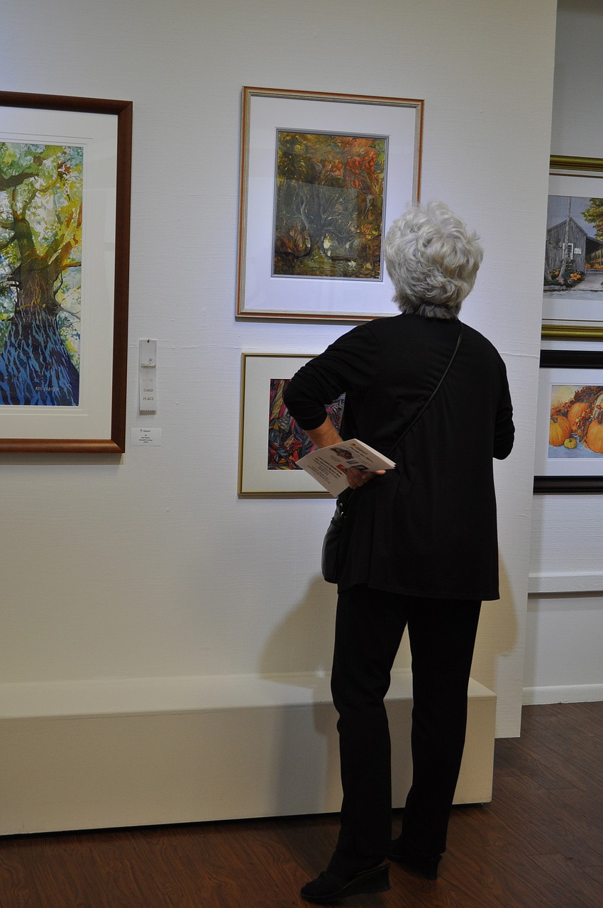 Arby Crawford from First Bank admires a wall of watercolor works