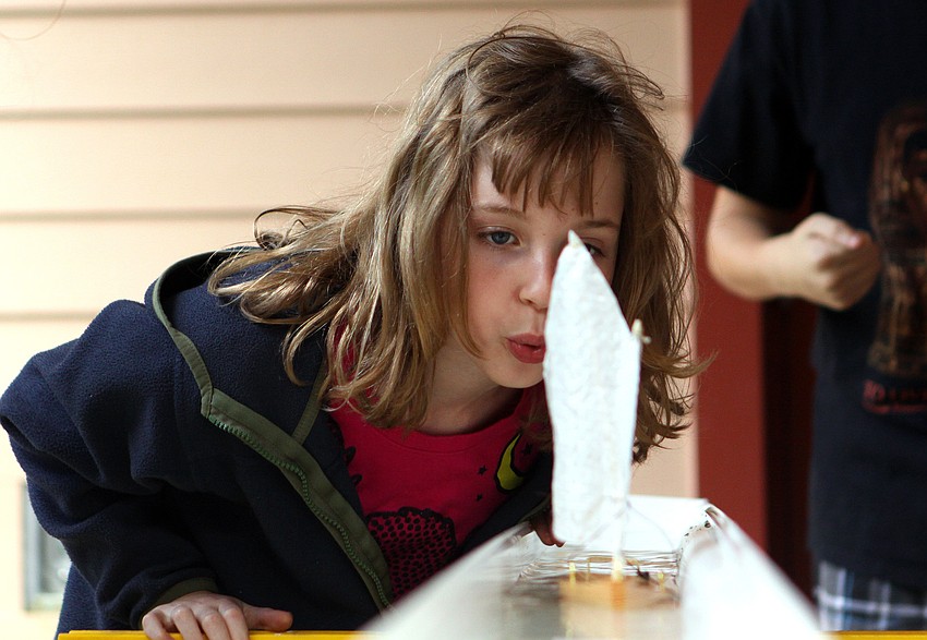 Katie Alcock, 8, blows on the sails of her boat during a boat race to 