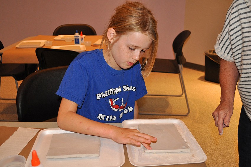 Tara Track, 8, starts to smooth out her clay slab prior to making her Florida fossil plaque Tuesday, Sept. 20, at the Selby Public Library.