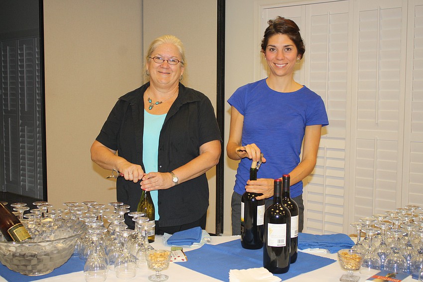 Mary Brown and Erica Cave uncork the wine for the celebration. They helped put the reception together following the service.