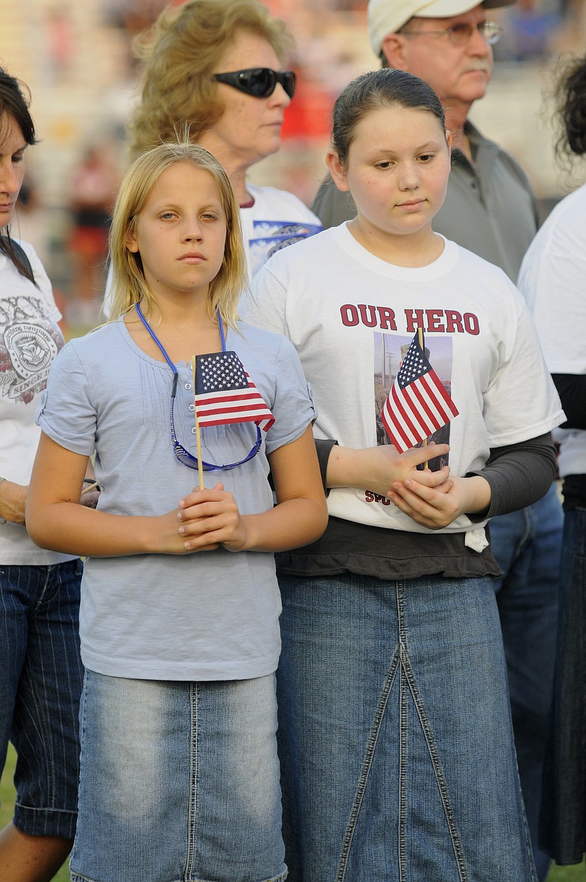 Shealeigh Gray, 11, and Adrianna Eason, 12, hold American flags in honor of their cousin, U.S. Army Spc. 4 Patrick Lay II.
