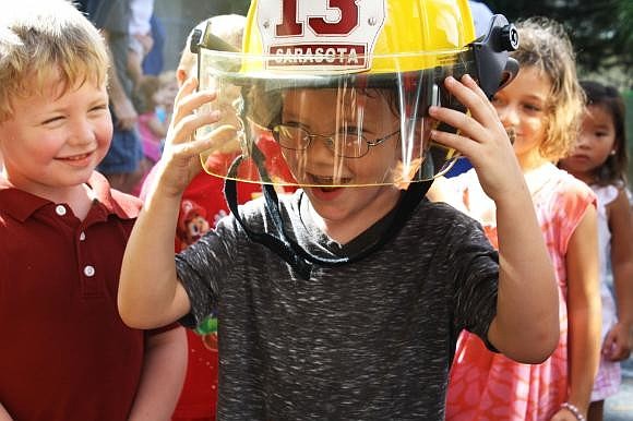 SIESTA KEY: Logan Lutz watches as Chance McArtor can barely support the weight of a firefighter helmet.