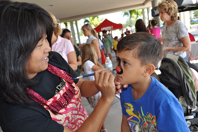 Akiko Campbell paints a spider on the face of Jacob Smith, 6.