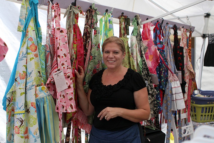Leah Jamison, owner of An Apron Story, poses with some of her favorite aprons Sunday, Oct. 16 on Main Street.