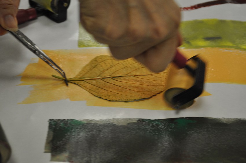 Tweezers keep fingers free of paint while the roller applies pigment to the textured leaf.