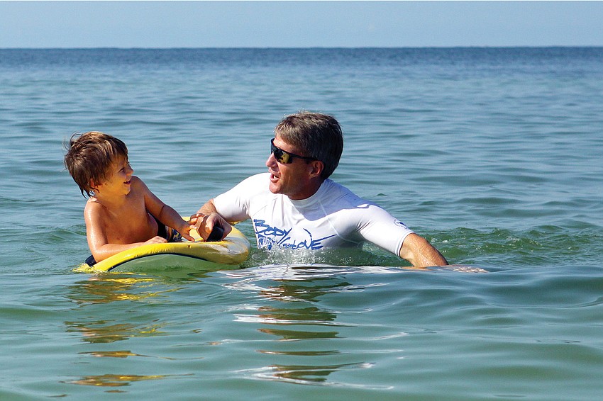 Aiden Seymour, 4, talked with his surf guide, Dan Runyo, before taking another wave at the second Hang Ten for Autism surfing event Sept. 17, on Siesta Key Public Beach. Published Sept. 22, 2011.