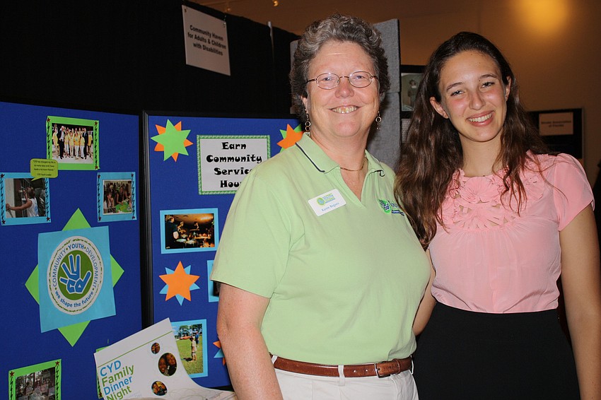 Executive Director Karen Bogues and student leader Sarah Brickman stand in front of their Community Youth Development booth.