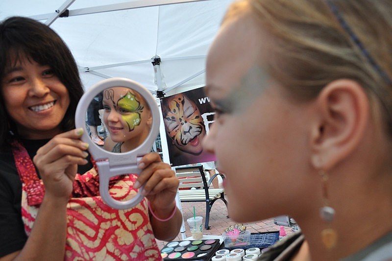Joeline Goldstein, 12, checks out the butterfly wing Akiki Campbell painted on her face.