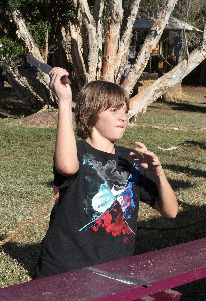 Giam Paolo Nicosia, 10, tries out his knife throwing skills, Sunday, Nov. 13, at the Sarasota Medieval Fair.