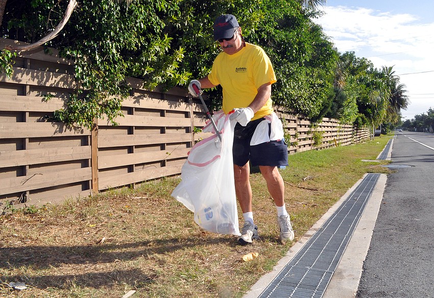 Michael Shay picks up bottles and glasses along Siesta Drive.