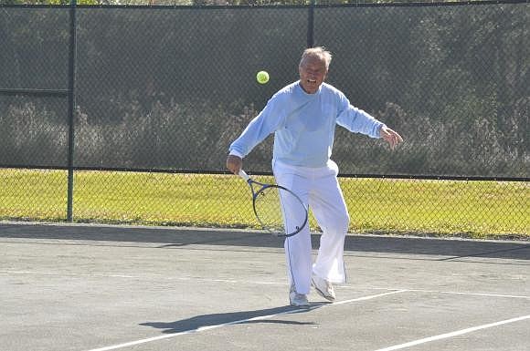 Jim Baker volleys a tennis ball. Photo by Mallory Gnaegy.