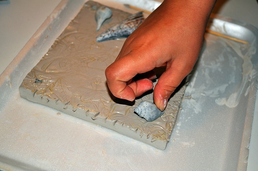 Natalie Dodge, 7, places a shell on her clay slab.