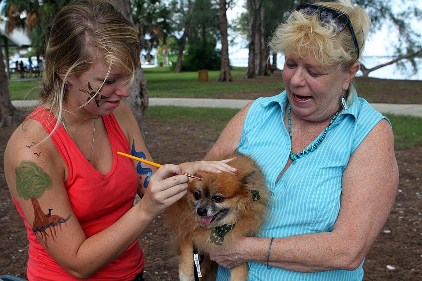 Kim Maguire does her best to paint a fish onto Dede Jonesâ€™ dog, Honey Buns, 7, Saturday, Sept. 24, at Ken Thompson Park.