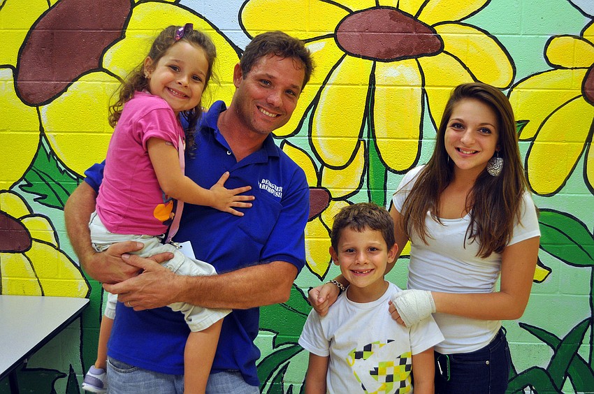 Anabelle Taylor, 5, Joe, John, 7, and Paulette, 13, pose in front of the sunflower mural after â€œFamily Dinner Nightâ€ Monday, Sept. 26, at the Lee Wetherington Boys & Girls Club.