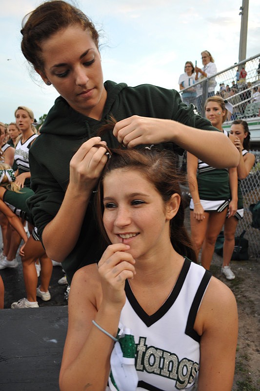 Senior Nicole Himmler helps fellow cheerleader Faith Williams, 15, get ready.