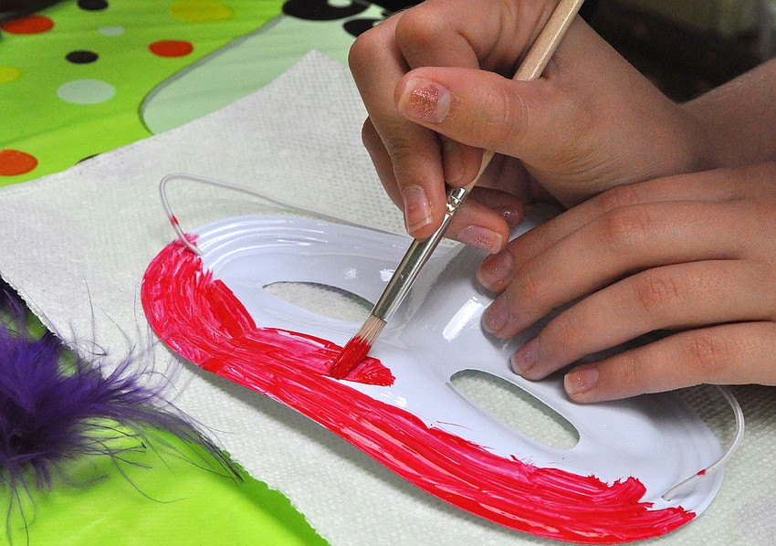 Hannah Leahy, 10, paints her mask red.
