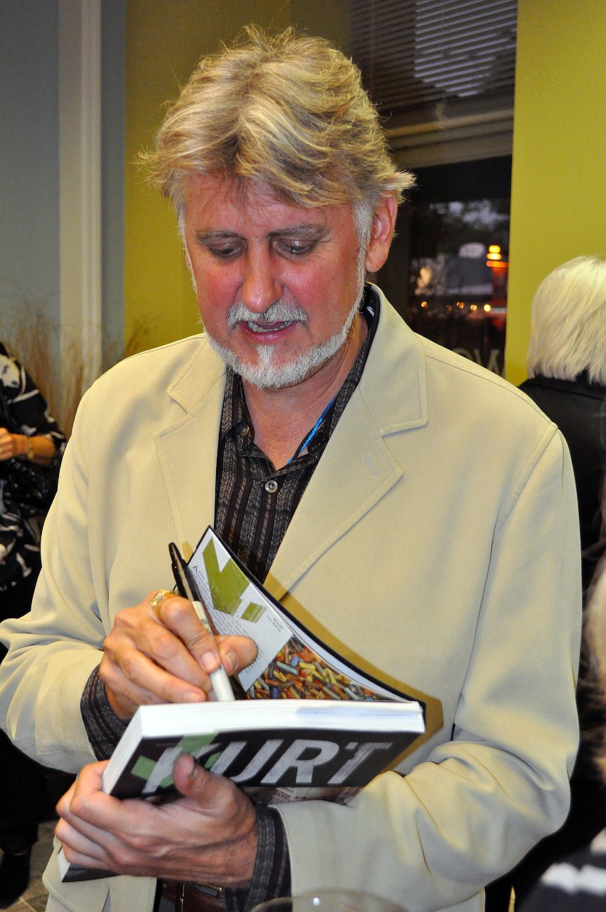 Kurt Wenner signs one of his books, Wednesday, Nov. 2, at J Wood Realty.