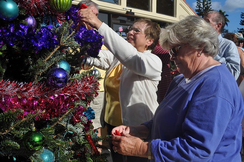 Joanna Zhurski and Eileen Cupolo add red bows to the branches