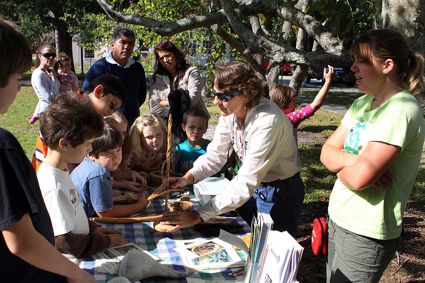 Karen Fraley of Around the Bend Nature Tours shows students some different tools that were used by Native Americans made out of wood, rocks and shells.