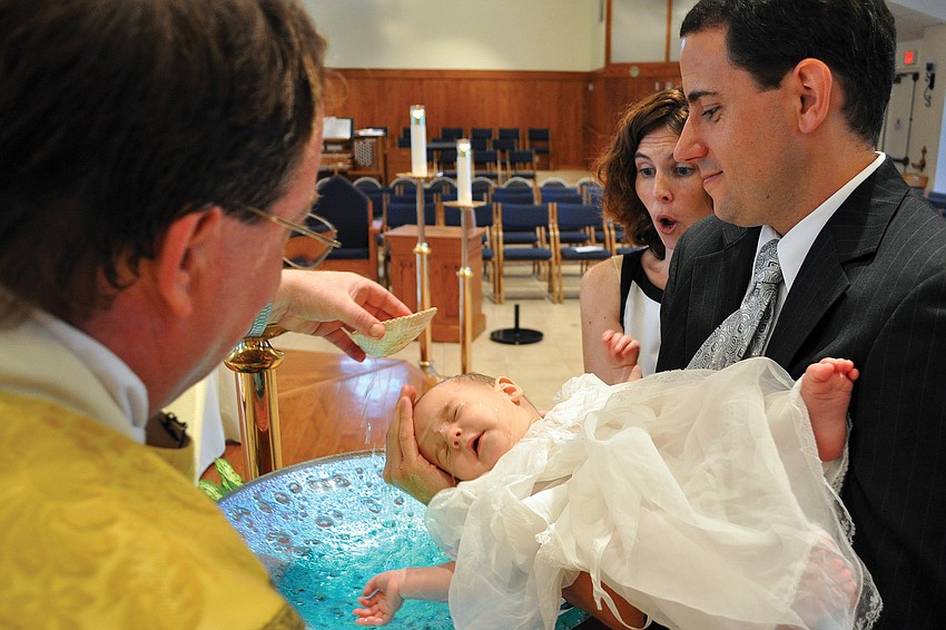 Lori Wolcott gasped while the Rev. Dan TK dumped the first bit of holy water onto her son, Colin Spencer, 6 months, during his baptism in June  at Our Lady of the Angels.