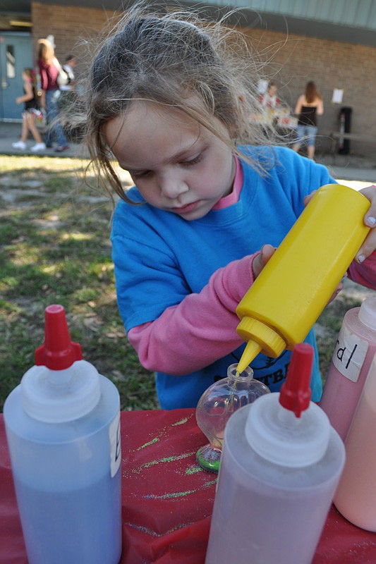 Alexis Wright fills a bottle with colored sand.