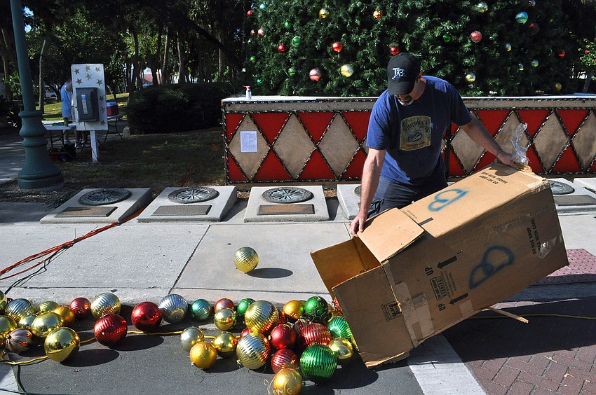 Mike Peffley spills out one of the many large cardboard boxes filled with ornaments onto the street during the tree decorating, Saturday, Nov. 19, out on the circle.