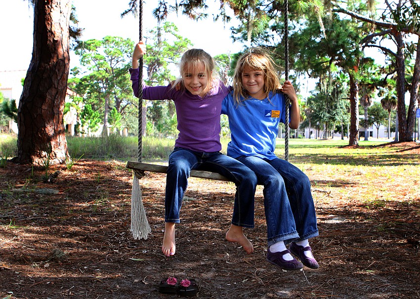 Caroline Gans, 7, and Miriam Baram, 7, swing on a wooden swing out behind New College's Public Archaeology Lab.
