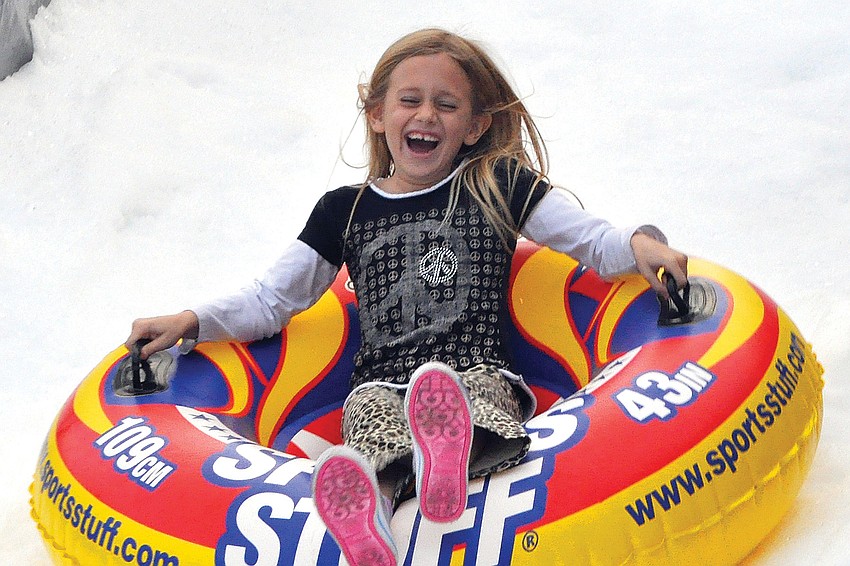 Blythe Snyder, 7, laughs as she goes down the snow slide in December at the South Village Holiday Stroll.