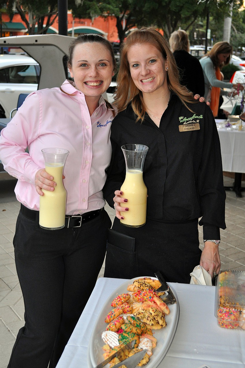 Megan Kelly and Jackie Linder of Sam Sneadâ€™s hold up some egg nog, which was served with cookies outside of the restaurant during the Southside Stroll.
