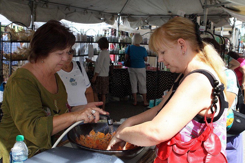 Shirley Wilson sprays water on Tamara Dobbsâ€™ hands after she rubbed some massage salts on her hands at the Pampered Hearts tent.