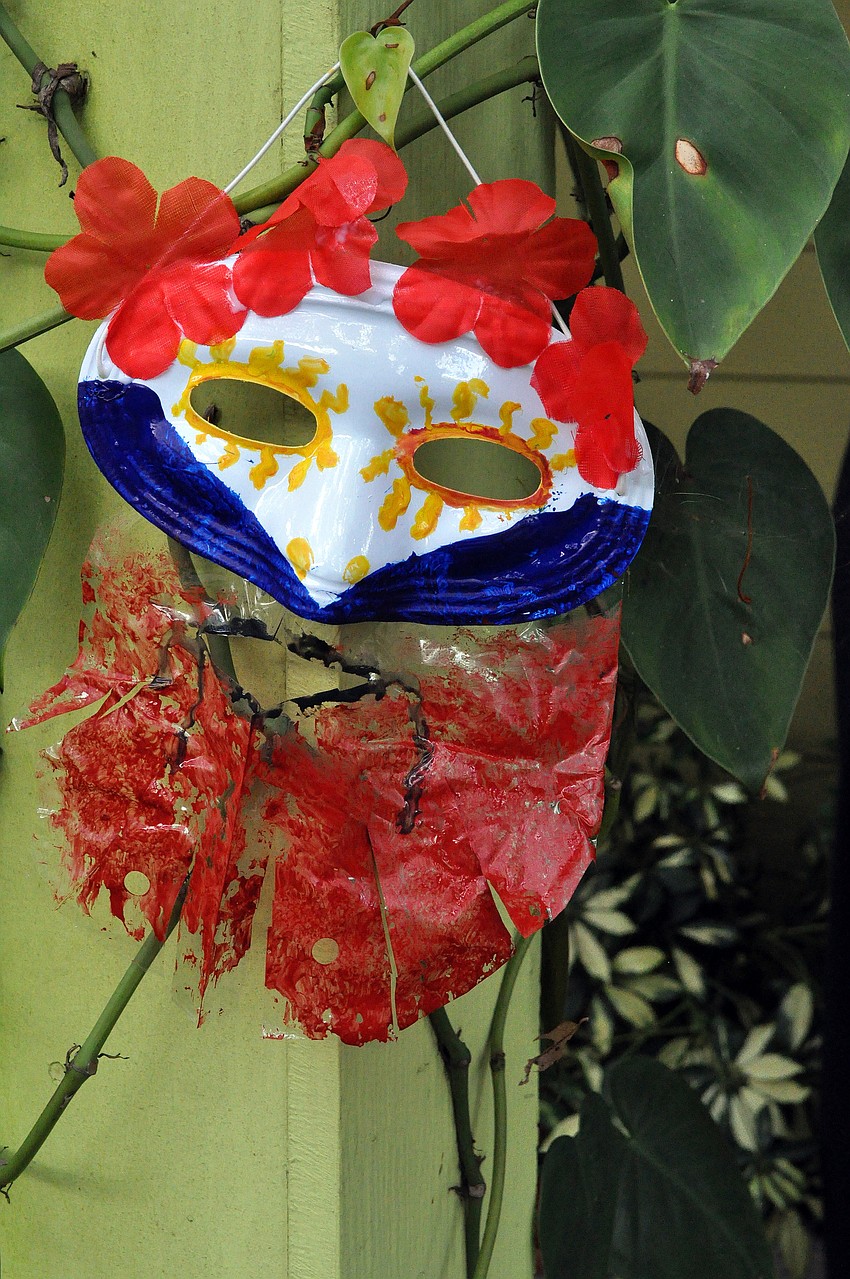 A very creative mask hangs outside on a vine to dry.