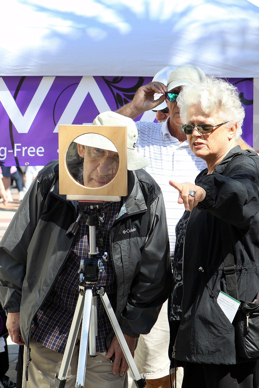 A couple looks through the glass lens at Rod Tryon's 3D piece.