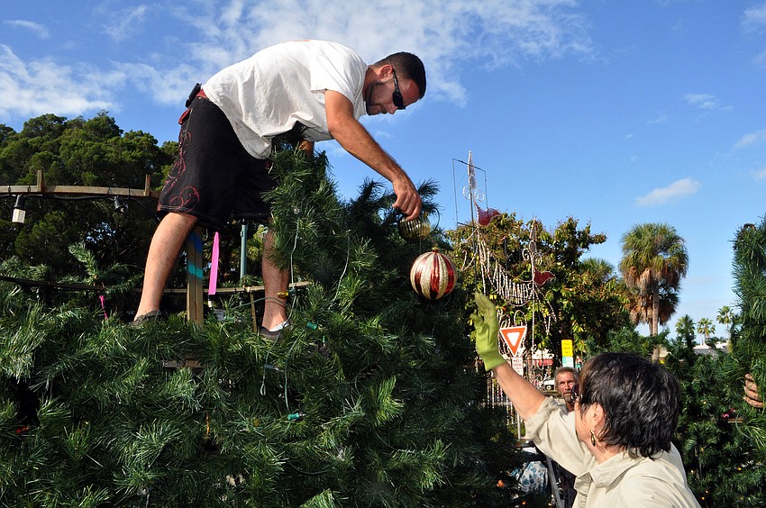 Louise Tessier hands up an ornament to Josh Trevino.