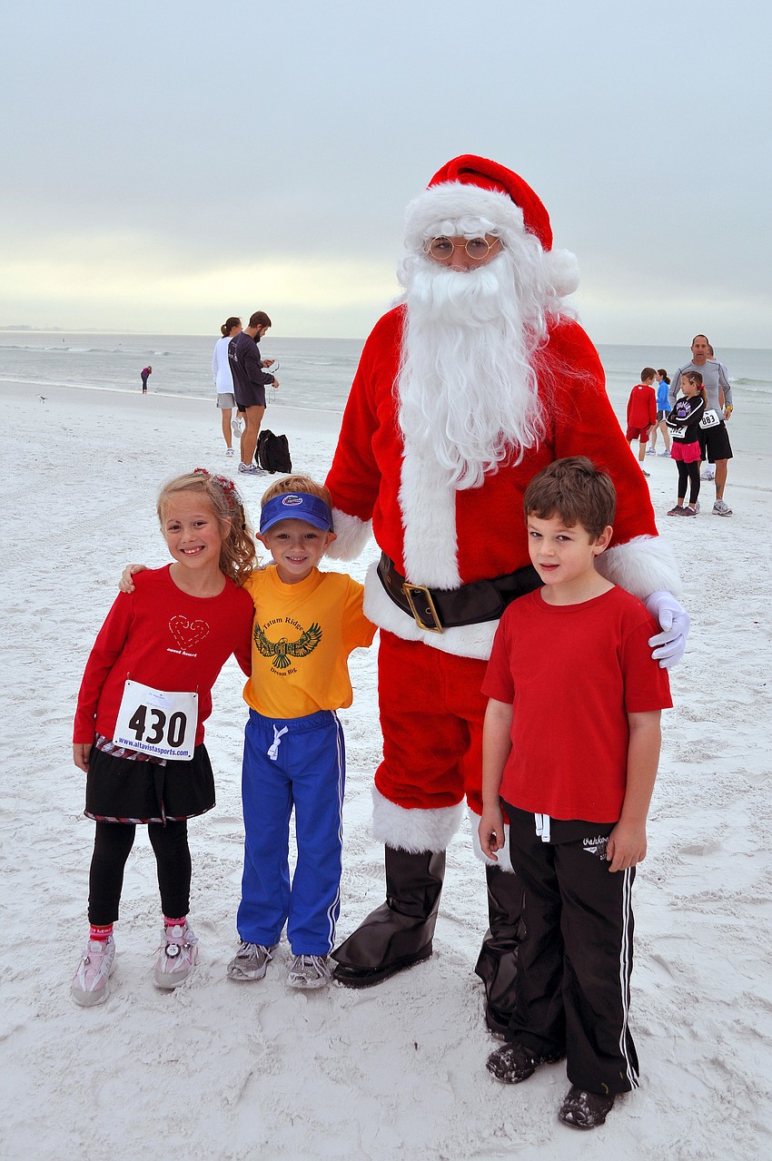 Sierra Miller, Jake Walker and Will Goodfellow, 6, pose with Santa Claus, Saturday, Dec. 10, at the 35th annual Sandy Claws run on Siesta Key Beach.