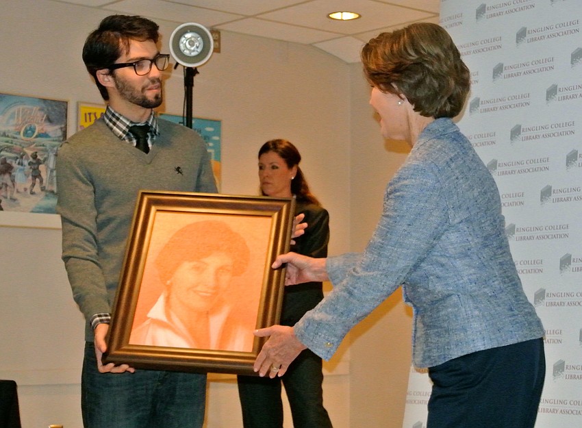 Former first lady Laura Bush accepts a portrait of herself from Ringling College of Art and Design student Andrew Theophilopoulos