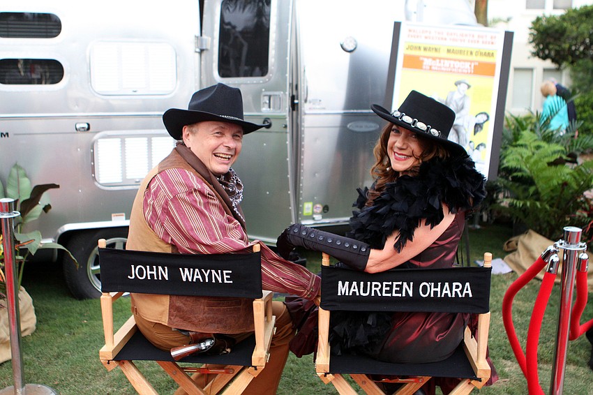 Dr. Larry Thompson and his wife, Pat, pose in movie star chairs labeled â€œJohn Wayneâ€ and â€œMaureen Oâ€™Haraâ€.