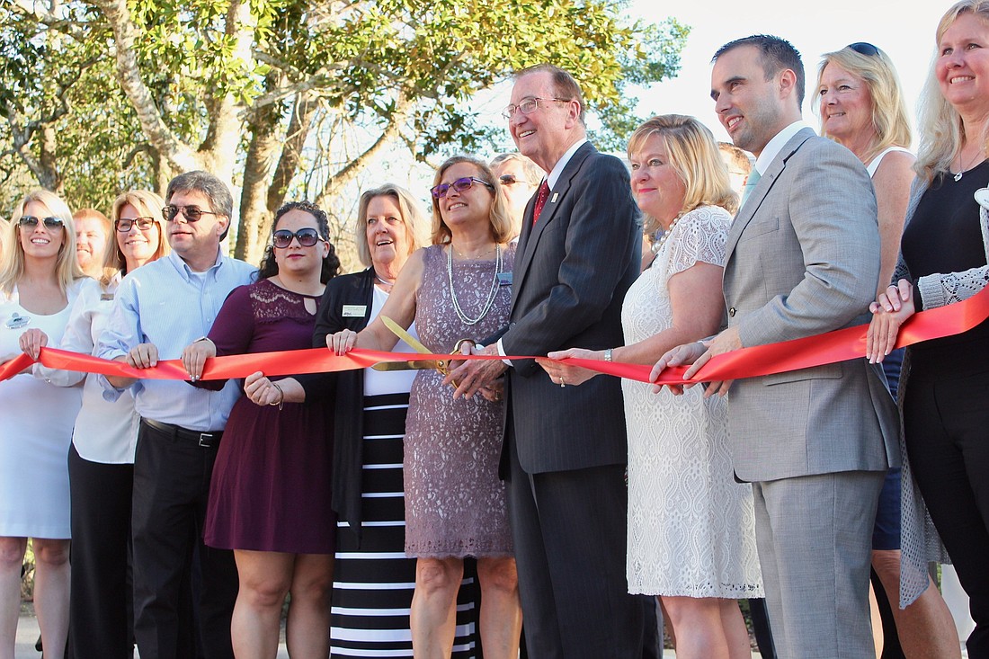 Bill Watson cuts the ribbon as Watson Realty Corp. employees celebrate the opening of the Hammock Beach office. Photo by Ray Boone