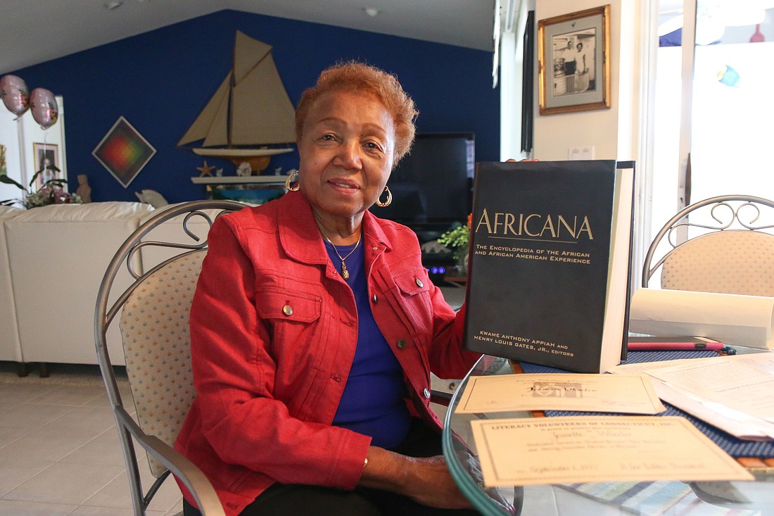 Jeanette Wheeler holds up a book she often refers: "Africana: The Encyclopedia of the African and African-American Experience." Photo by Paige Wilson