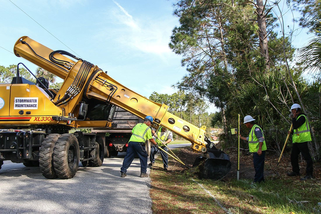 City of Palm Coast workers John Caccavale (machine operator), Bobby Pearson, John Delbonis and Jeffrey Starr, and part-time employee Deshawn Barbero repair the swale on Providence Lane in Palm Coast. Photo by Paige Wilson