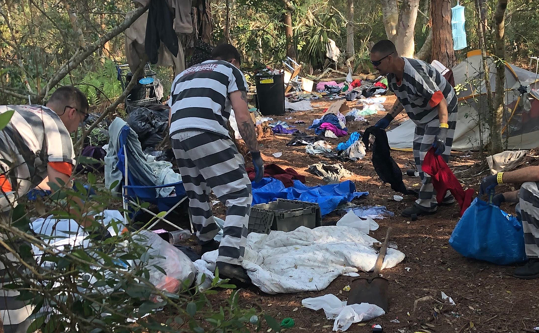 Inmate Work Crew members working on clearing trash from the woods behind the Flagler County Public Library. Photo courtesy of the Flagler County Sheriff's Office