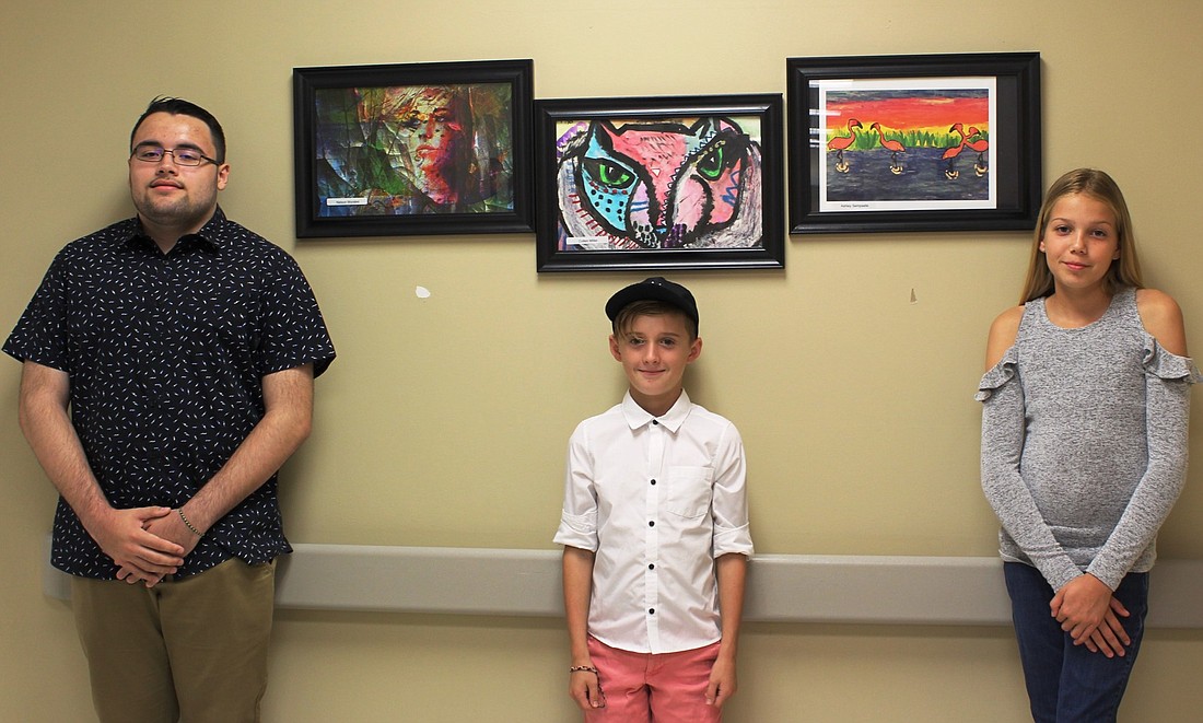 Flagler Palm Coast High School senior Nelson Morales, Wadsworth Elementary School fifth grader Colten Miller and Indian Trails Middle School seventh grader Ashley Sempselle stand with their art. Photo courtesy of AdventHealth