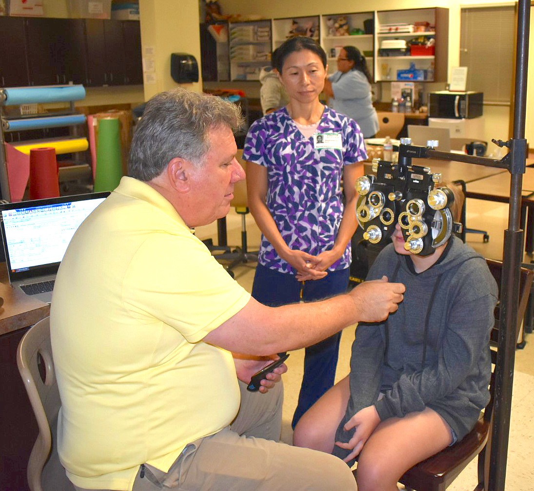 School Health Coordinator Stephanie Ear looks on as an optometrist from Florida Heiken screens a student. Courtesy photo